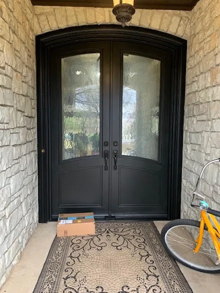 Arched double front door refinished in black on a stone entry