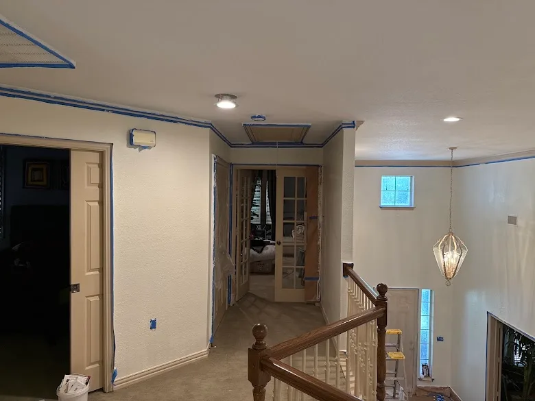 Upstairs hallway taped and prepped for interior painting with clean lines along the ceiling